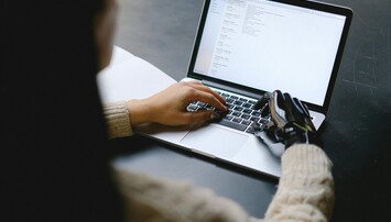 Persoon met gemotoriseerde hand voor laptop